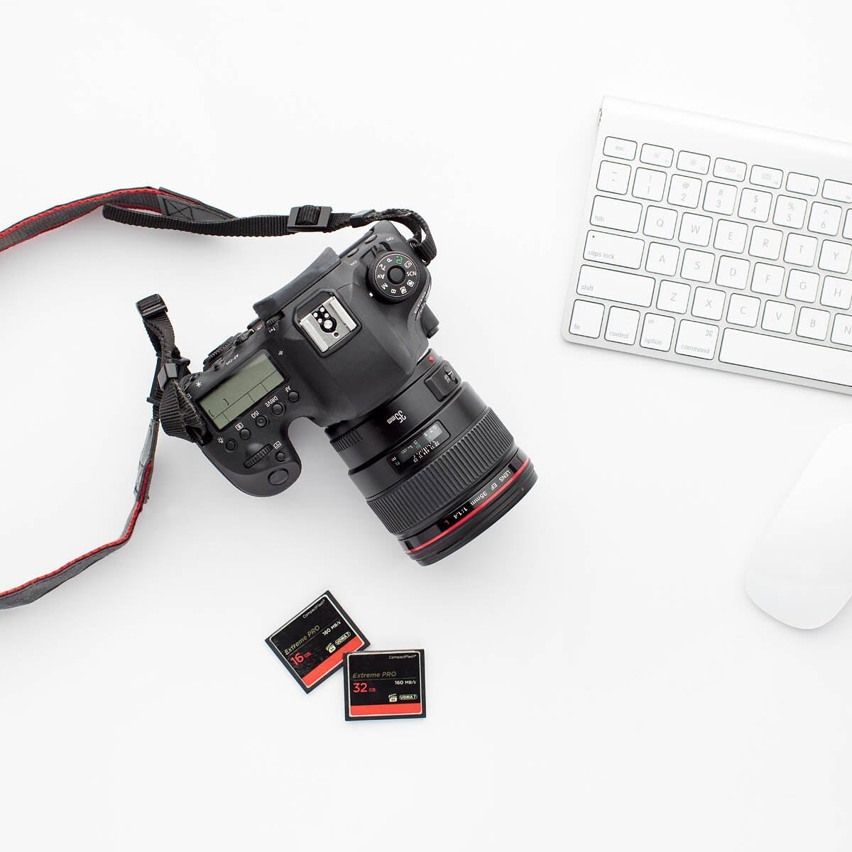 camera laying on desk with sd cards and a keyboard