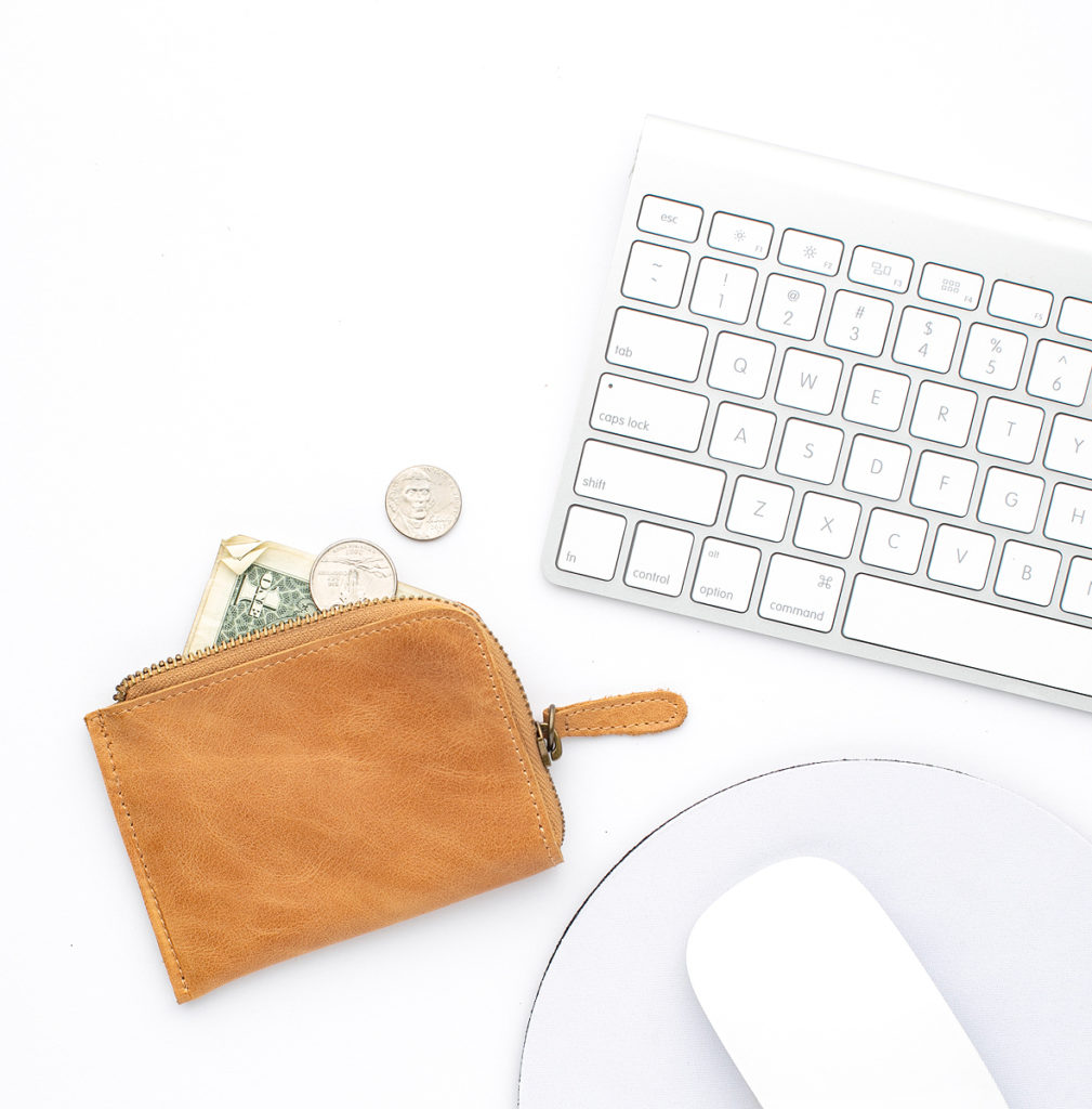 image of keyboard, computer mouse, and light brown leather change purse with money spilling out