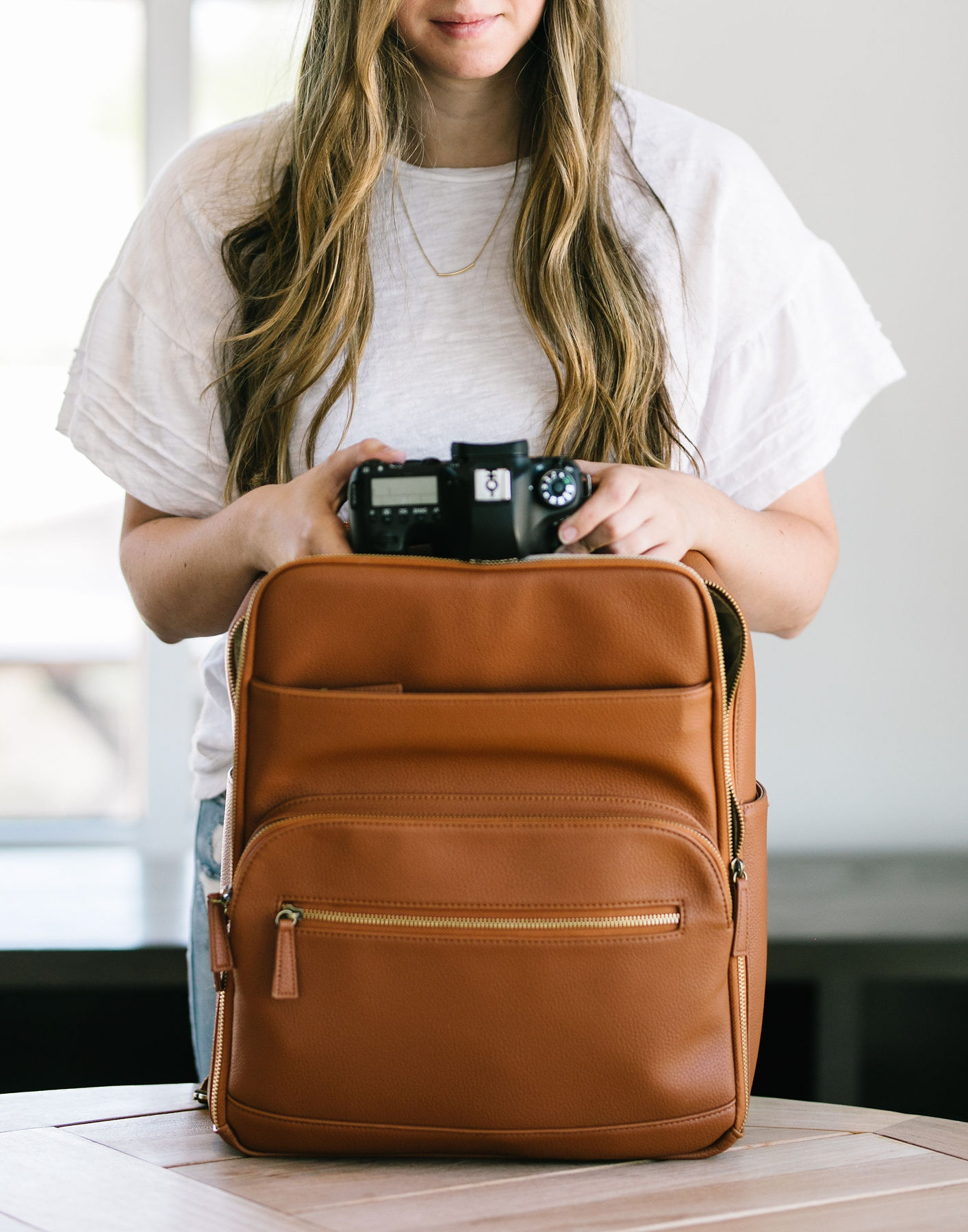 woman putting a camera in a leather bag